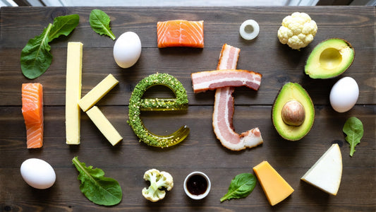 Healthy meals in Kolkata shown with keto foods like salmon, avocado, eggs and greens on wood table.